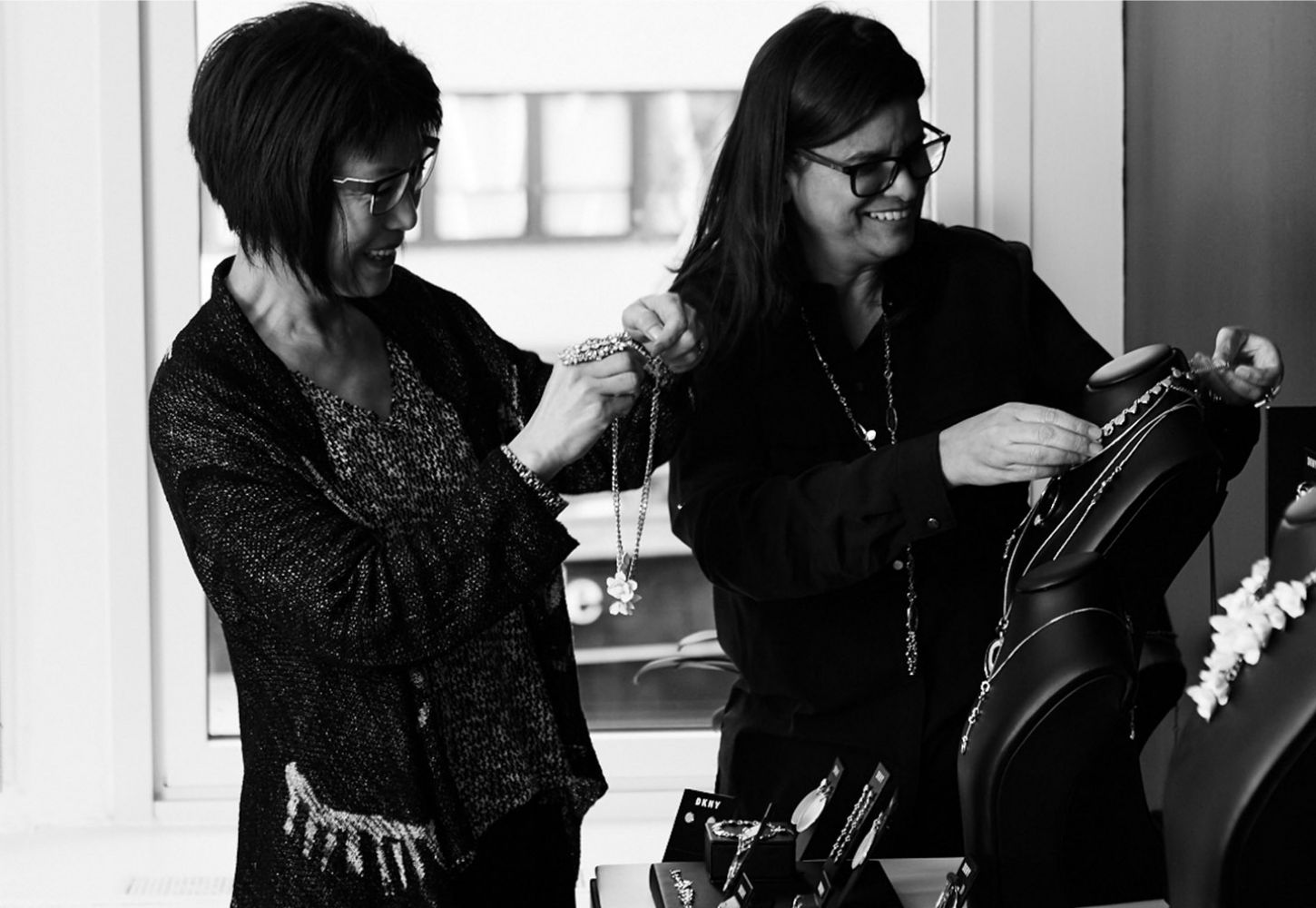 Women in showroom placing Jewelry on mannequin