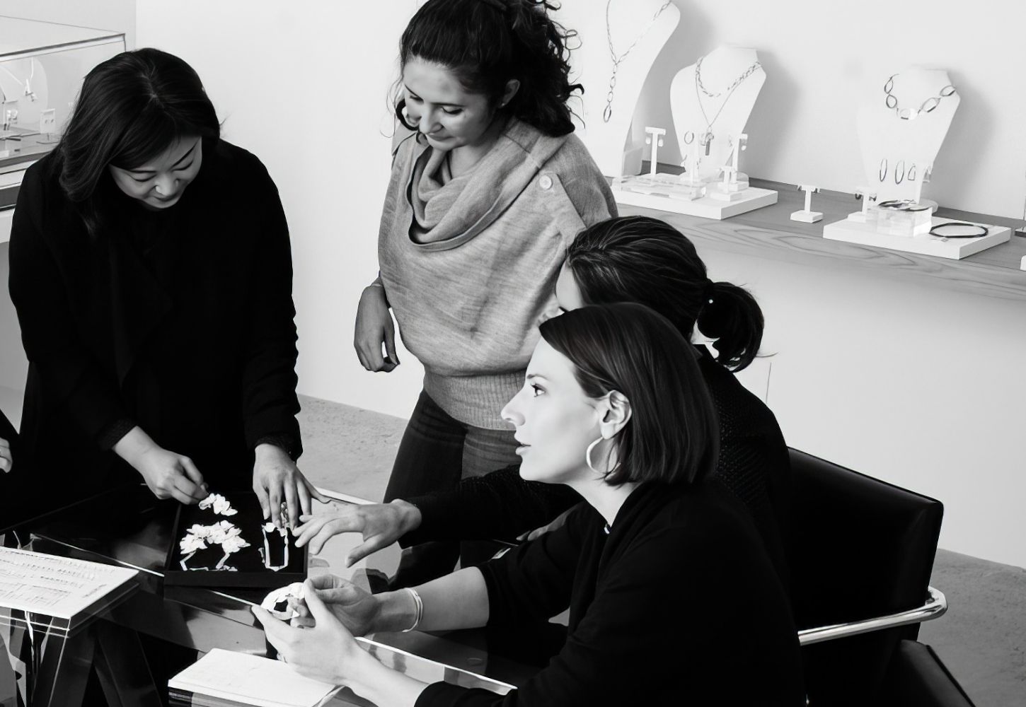 Women in showroom at work desk inspecting jewelry