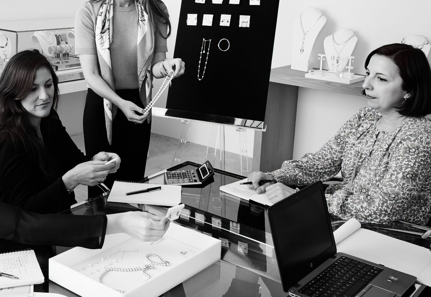 Women in showroom at work desk inspecting jewelry