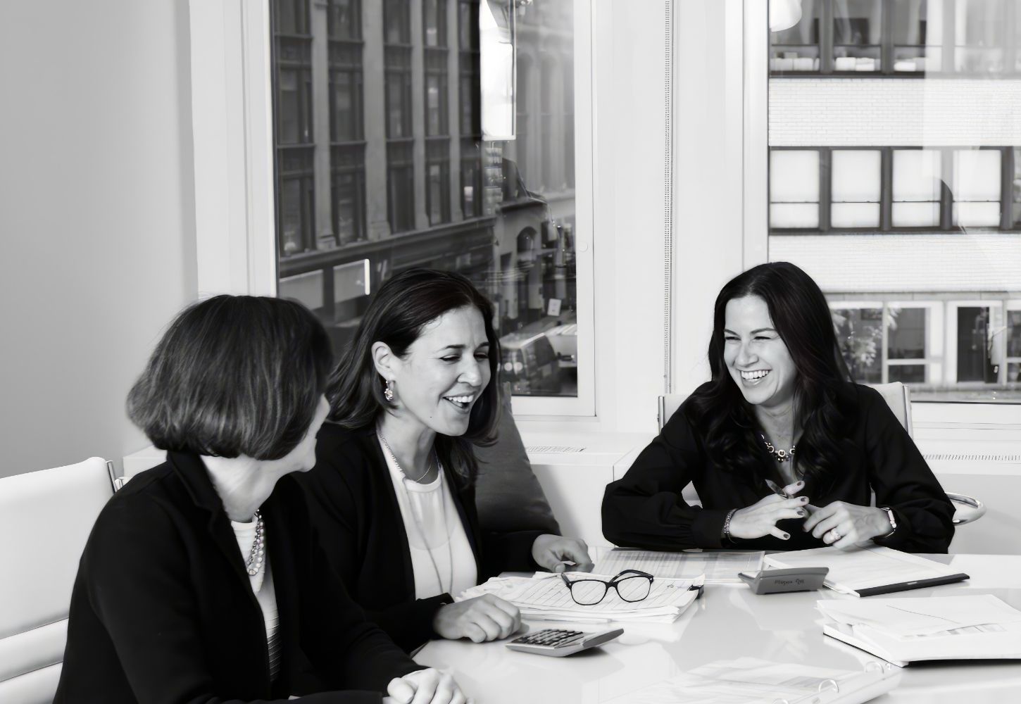 Women in showroom smiling at work desk during conversation